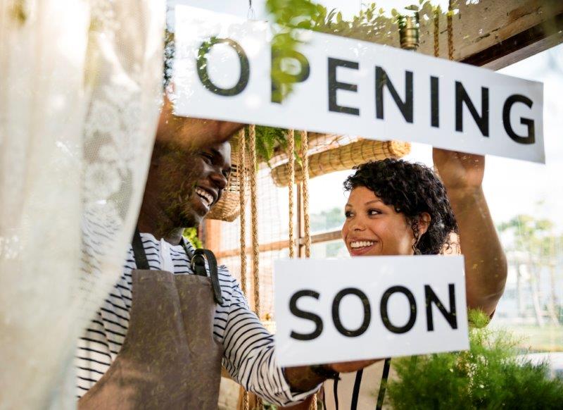 Business owners hanging a sign that reads opening soon